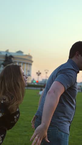 Happy couple playing in the summer field. They enjoy each other. Smile, laugh. Supr slow motion shot. Sunset or sunrise natural lighting. Man-horse riding joke. Vertical shot.