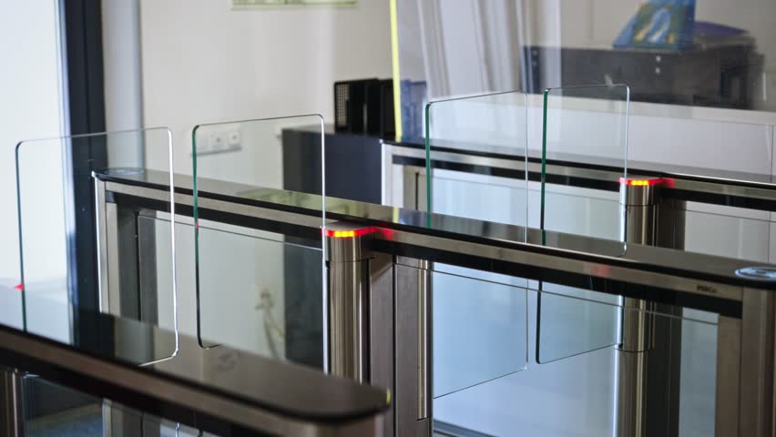 Passing through a turnstile into an office building. Office workers enter and exit through a modern turnstile, using a key card to enter.