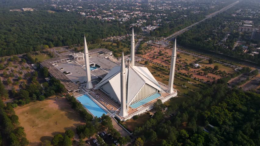Aerial view of Shah Faisal Mosque surrounded by greenery and urban landscape, Islamabad, Pakistan.