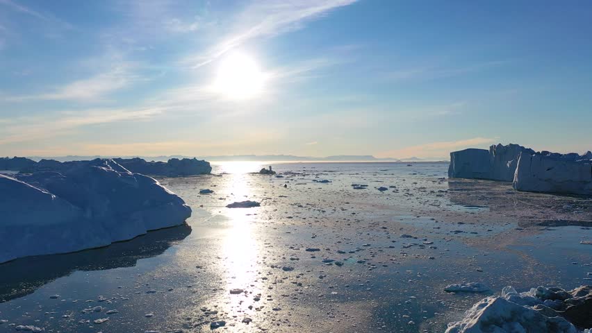 Massive icebergs and tranquil waters reflect the beauty of a polar landscape in north Greenland during mid-afternoon