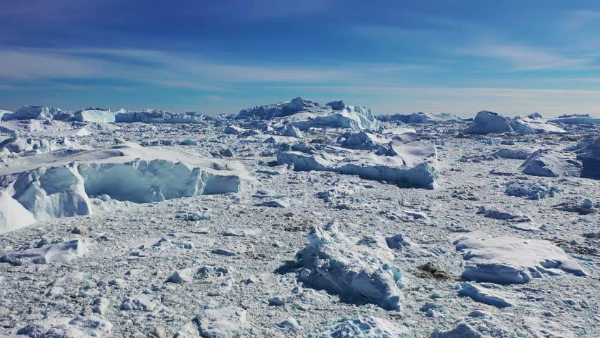 Massive icebergs and tranquil waters reflect the beauty of a polar landscape in north Greenland during mid-afternoon