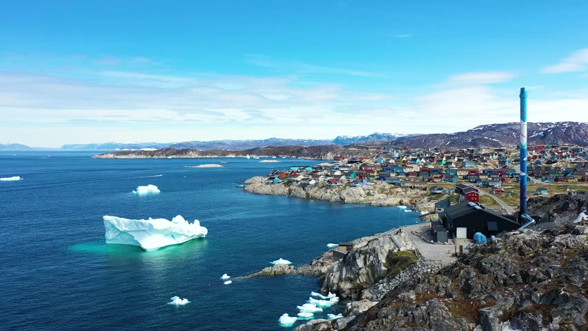 Massive icebergs and tranquil waters reflect the beauty of a polar landscape in north Greenland during mid-afternoon