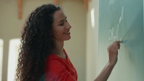 Smiling clever Hispanic student girl Latina woman Caucasian female lady teacher tutor studying learn writing chalk on blackboard formula math mathematic in class auditorium university college academy - Powered by Shutterstock - Get 15% off with code: PIKWIZARD15