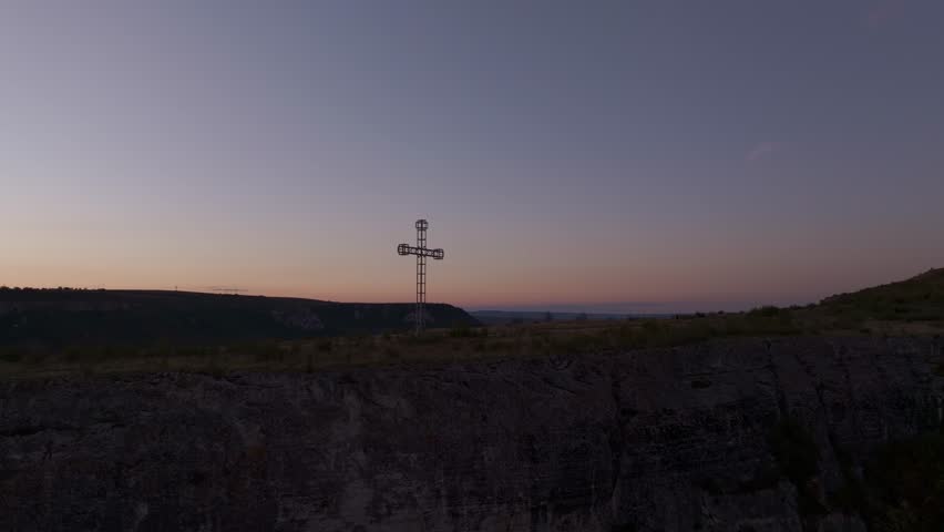 Aerial view of Ovech Fortress at sunset with a tranquil sky and silhouetted cross, Provadia, Bulgaria.
