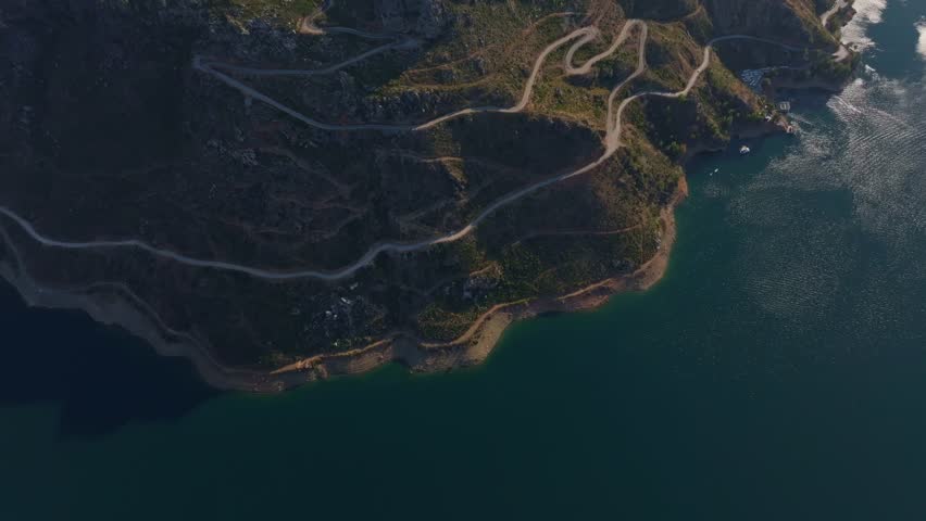 Aerial view of the beautiful Green Canon with a serene lake, winding road, and rugged terrain, Manavgat, Turkey.
