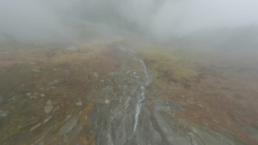 FPV drone flies quickly through the fog close to the stone surface. Austria