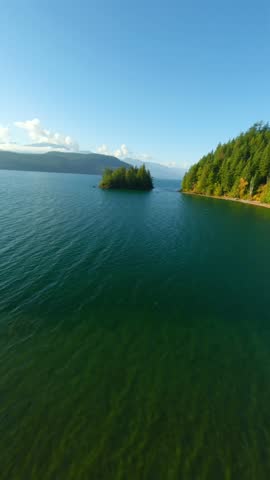 FPV Aerial view of colourful forest on mountain slopes and Harrison Lake. Canada
