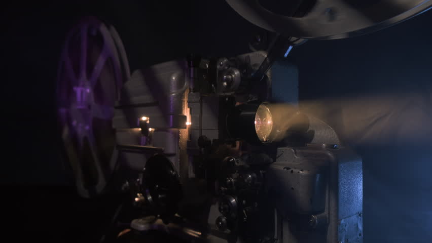 Old 16mm film projector with diffuse light beam, movie screening.
