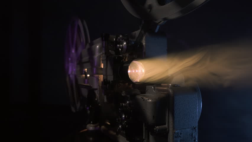 Old 16mm film projector with diffuse light beam, movie screening.