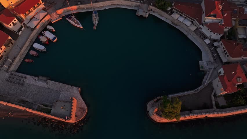 Aerial view of Nafpaktos Venetian Port at sunrise with beautiful medieval architecture and tranquil water, Nafpaktos, Greece.