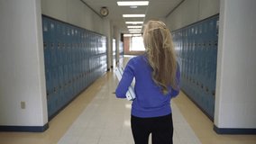A middle-aged teacher walks confidently down a school hallway, holding books. The lockers line the walls, reflecting a typical school environment during the day. - Powered by Shutterstock - Get 15% off with code: PIKWIZARD15