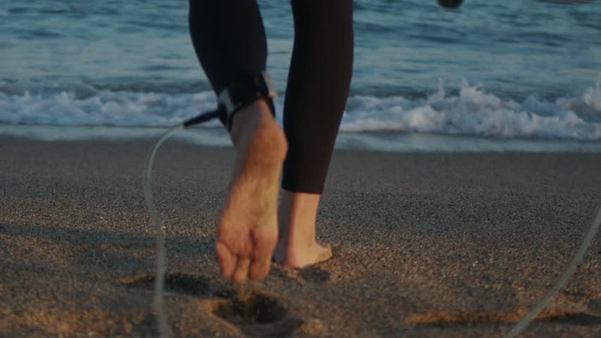 Surfer man walking to the beach at sunset preparing for surfing training and search for waves in Barcelona, spain, water, ocean exercise in sea with board, athletic male holiday or travel in vacation.