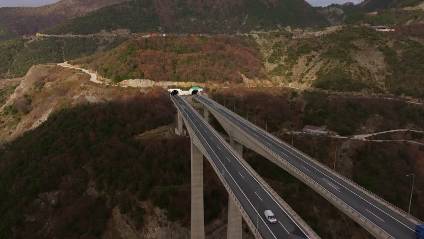 Aerial view of highway and tunnel surrounded by beautiful mountains and forest in autumn, Metsovo, Greece.