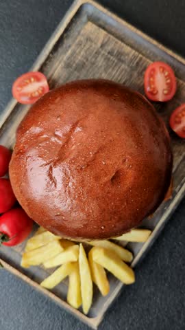 Delicious burger with beef patty, fried egg, bacon, herbs, sauce, salt and spices on dark concrete background