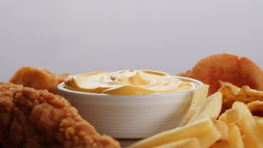 Curry cheese lemon sauce close up, fast food cafe Pouring fries potato and fry chicken in mayo yellow creamy cheese sauce close-up. Eat chicken nuggets with Peruvian sauce. Fast and junk food concept.