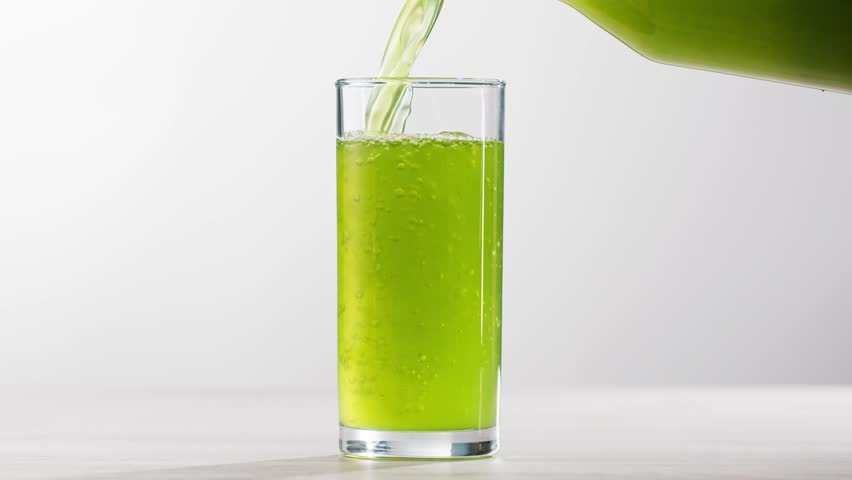 Fresh Green detox juice with cucumber, celery, apple and ginger and mint in glasses and jars. Pouring Vegan juice detox concept.