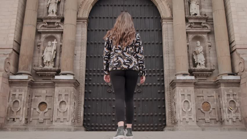 A Woman Walking Towards The Front Door Of Lima Cathedral In The Lima District, Peru. Pan Up Shot
