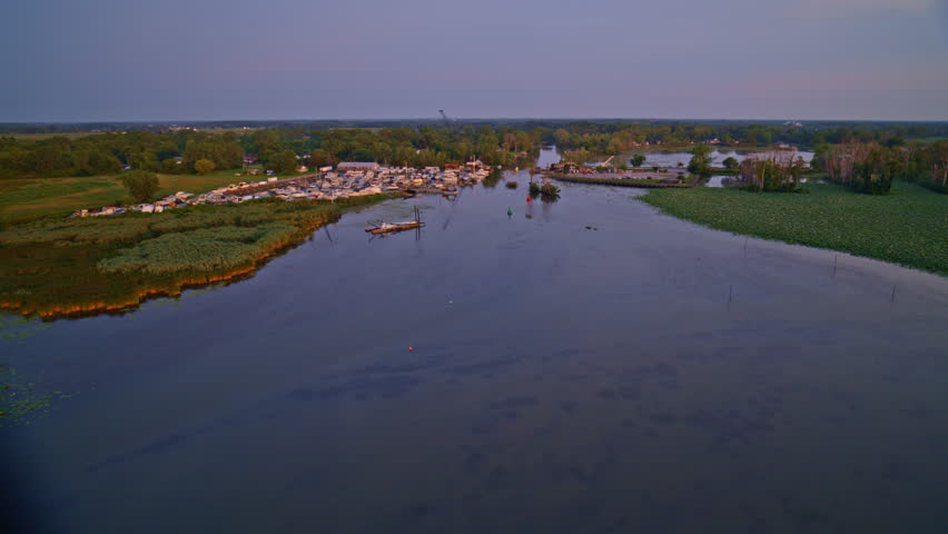 Drone shot flying over lake erie back towards the mouth of the huron river as it enters the lake at sunrise