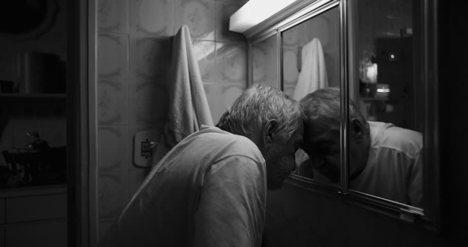 Elderly man pressing his head against a bathroom mirror, consumed by exhaustion and the crushing weight of emotional anguish, in a raw and dramatic display of vulnerability, monochrome