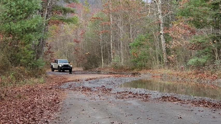 Rural country dirt road pickup truck driving through mud in mountains 