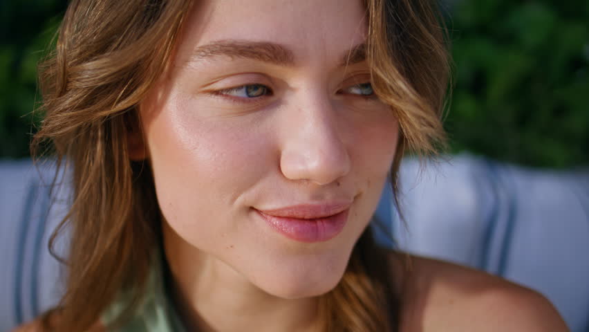 Closeup cheerful woman smiling gently surrounded by green ivy leaves. Happy beautiful lady looking camera adjusting wind blown hair. Portrait of sensual model posing in serene outdoors setting alone.