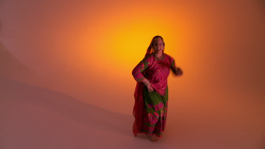 Indian girl in traditional folk costume against an orange colored background
