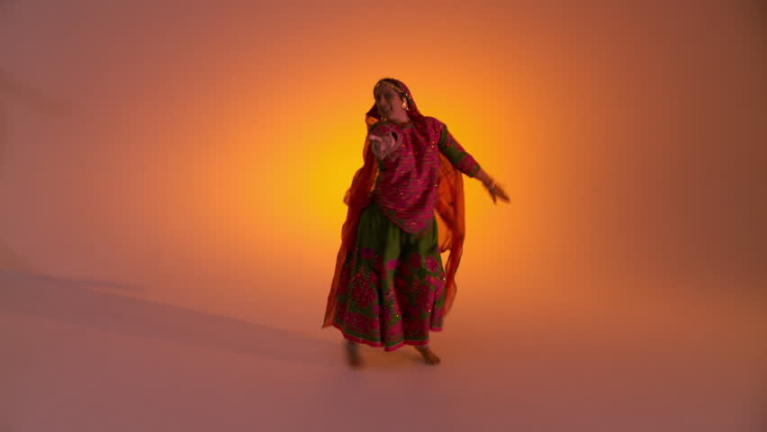 Indian girl in traditional folk costume swirls her skirts as she dances against