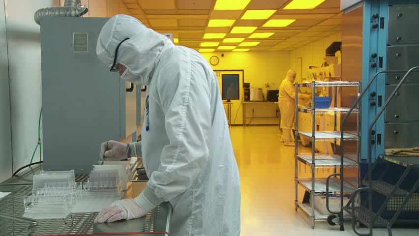 Technician in full-body coveralls sorts out silicon wafers and prepares them to