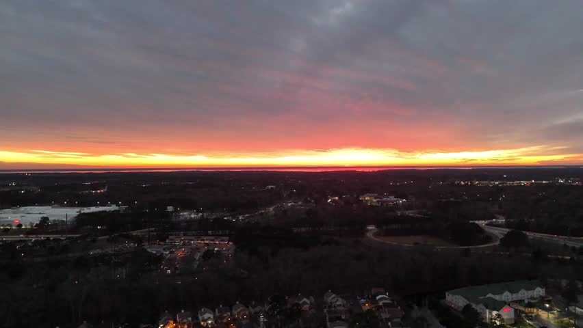 A radiating burst of light exploding through the cracks of an overcast sky just over the horizon as the sun begins to set and the view begins to rise