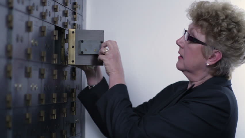 Woman opens up a safe deposit box and removes contents. Medium close up inside