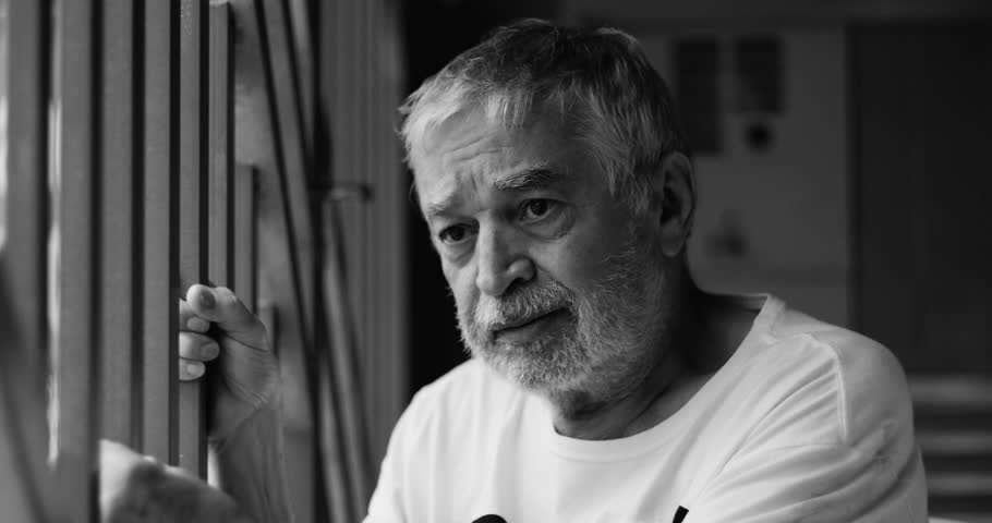 Elderly man in garage leaning on metal bars, crying in sorrow and hopelessness, expressing deep sadness and solitude, reflective moment of desperation and despair, black and white