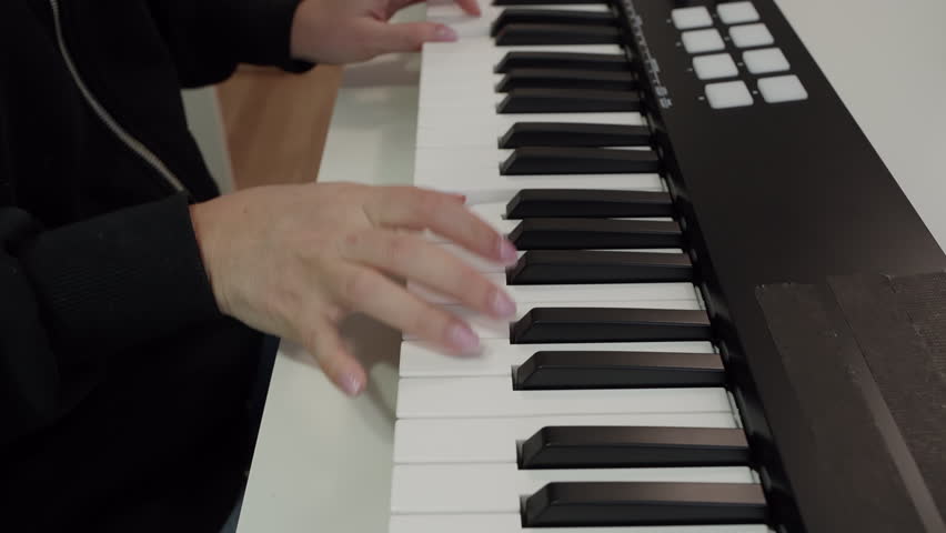 Closeup of woman female fingers palm hands playing keyboard. Female pianist is enjoying music. She is wearing long sleeves casual.