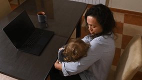 Young mother working remotely while embracing her child in a warm moment - Powered by Shutterstock - Get 15% off with code: PIKWIZARD15