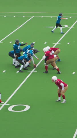 Vertical Screen: Male Athletes Competing in an Intense American Football Game on a Green Field, Showing Teamwork and Strategy. Players in Red and Blue Jerseys Engage in Dynamic Plays and Formations