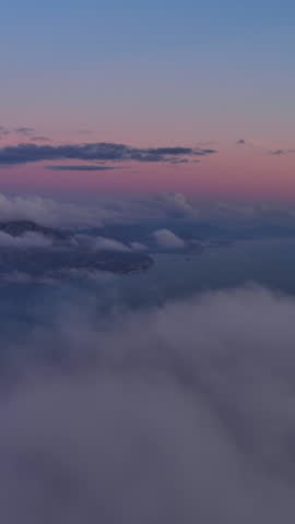 Aerial view on Adriatic sea coast with mountains and Budva city in Montenegro and dusk clouds. Travel seascape background and nature landscape. Vertical video