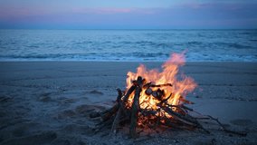 Warm flames of a campfire illuminate a peaceful sandy beach with a calm sea and soft twilight in the background. Ideal for travel, adventure, and serenity concepts - Powered by Shutterstock - Get 15% off with code: PIKWIZARD15