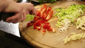 Red pepper, Fresh produce, Culinary prep. Hand is shown slicing red bell pepper on wooden cutting board, surrounded by assortment of chopped vegetables and fresh herbs. - Powered by Shutterstock - Get 15% off with code: PIKWIZARD15