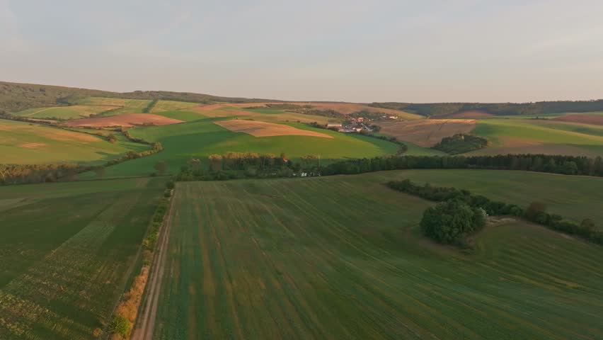 Aerial view of picturesque fields and rolling hills at sunrise with a windmill, Kunkovice, Czech Republic.