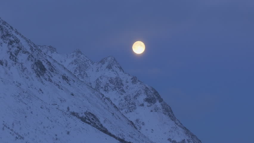Bright full moon looms over snow covered mountain in Lofoten, Norway, majestic natural arctic scenery