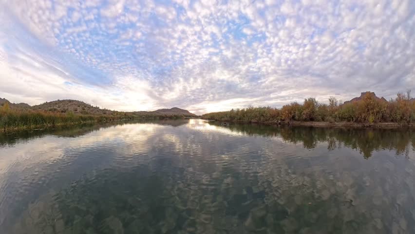 Sunsets over a river in Mesa Arizona with Saguaro and Mesquite trees.