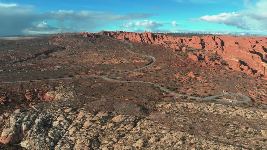 A stunning aerial red rock landscape shot with a bright blue sky in the background and thick storm clouds rolling in