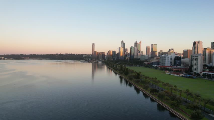 Aerial view of a vibrant cityscape with modern architecture and calm water reflections at sunset, Perth, Australia.