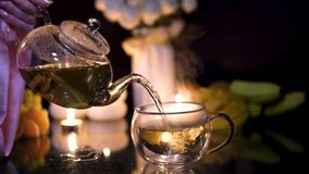 A glass teapot with whirling warm tea, cranberries, and citruses on a cozy table with a flickering candle nearby. Winter holidays, snow falling outdoors - Powered by Shutterstock - Get 15% off with code: PIKWIZARD15