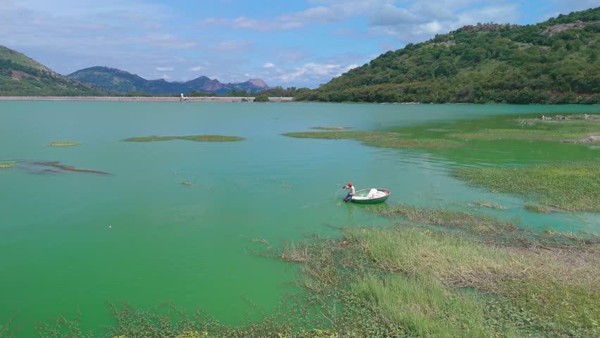 Aerial view of fisherman fishing in small boat in dam, India