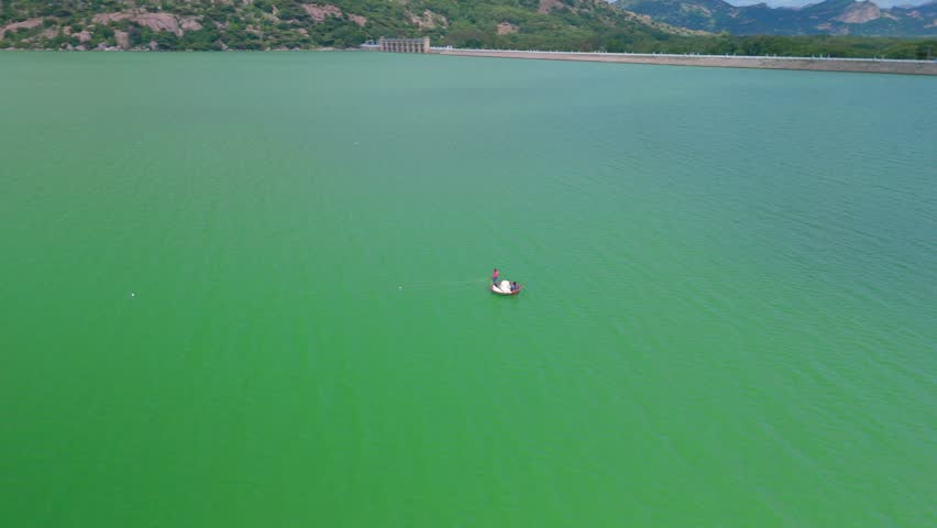 Aerial view of fisherman fishing in small boat in dam, India