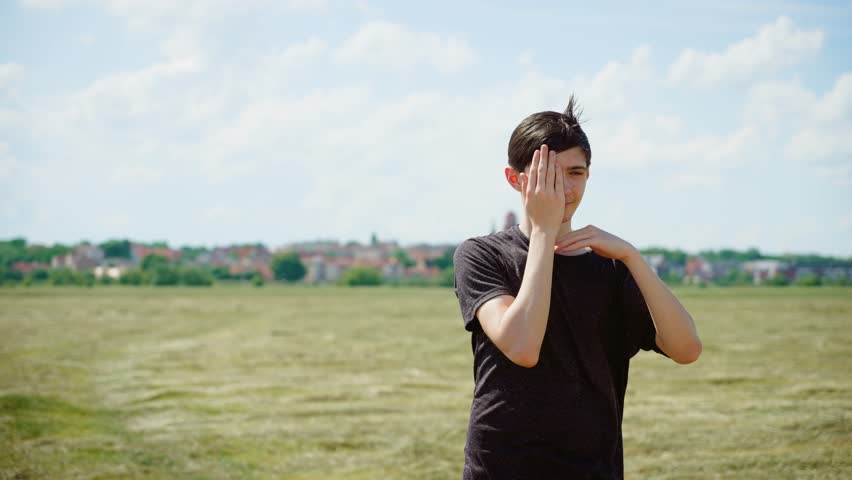 Teenage boy dancing head dance, moving hands around face, closing eyes. Young male performing head dance, gesturing with hands around face, eyes shut. Boy making head movements, framing face with
