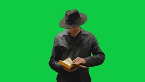 A figure in a black coat and tilted fedora is engrossed in a book, their face hidden in the shadows. The green screen backdrop allows for easy compositing into any scene - Powered by Shutterstock - Get 15% off with code: PIKWIZARD15