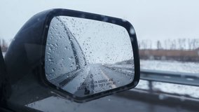 Side mirror of moving car covered water drops from melting snow reducing visibility in snowy weather. Driving on highway in countryside bad visibility - Powered by Shutterstock - Get 15% off with code: PIKWIZARD15