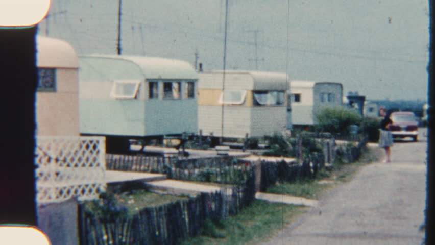 Cozy mobile homes nestled in a scenic park, each with inviting outdoor spaces surrounded by greenery, perfect for relaxation and leisure, captured on 8mm film