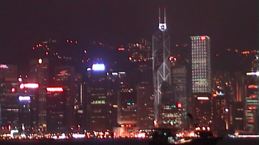 A vintage video with a grainy, slightly distorted appearance captures the Hong Kong skyline, featuring a blend of modern, angular skyscrapers and historic architecture